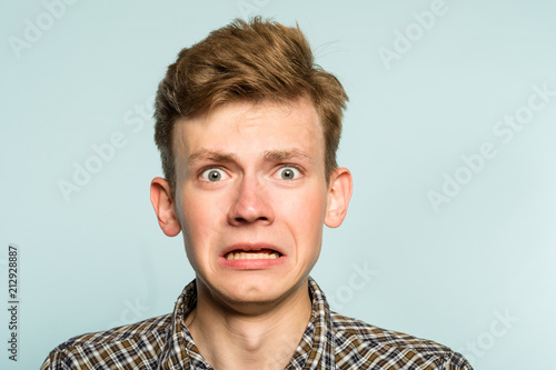 awkward gawky fumbling oafish dorky man facial expression. portrait of a young guy on light background. emotion facial expression. feelings and people reaction. photo