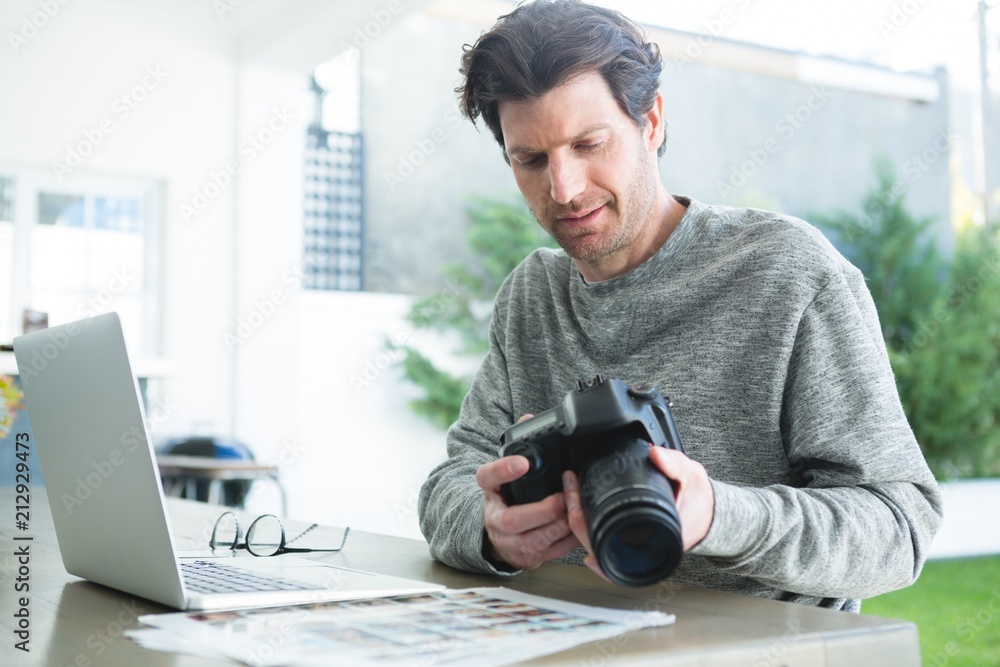 Man using laptop and holding digital camera Man using laptop and holding digital camera