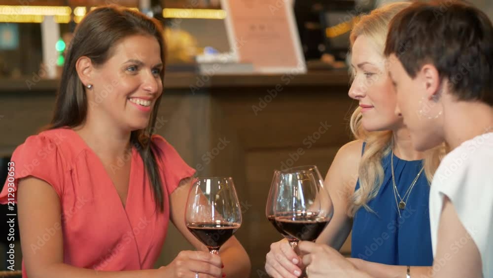 people, celebration and lifestyle concept - happy women drinking red wine and talking at restaurant or bar people, celebration and lifestyle concept - happy women drinking red wine and talking at restaurant or bar