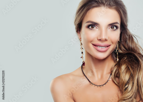 Beautiful smiling woman with gold jewelry necklace and earrings with garnet