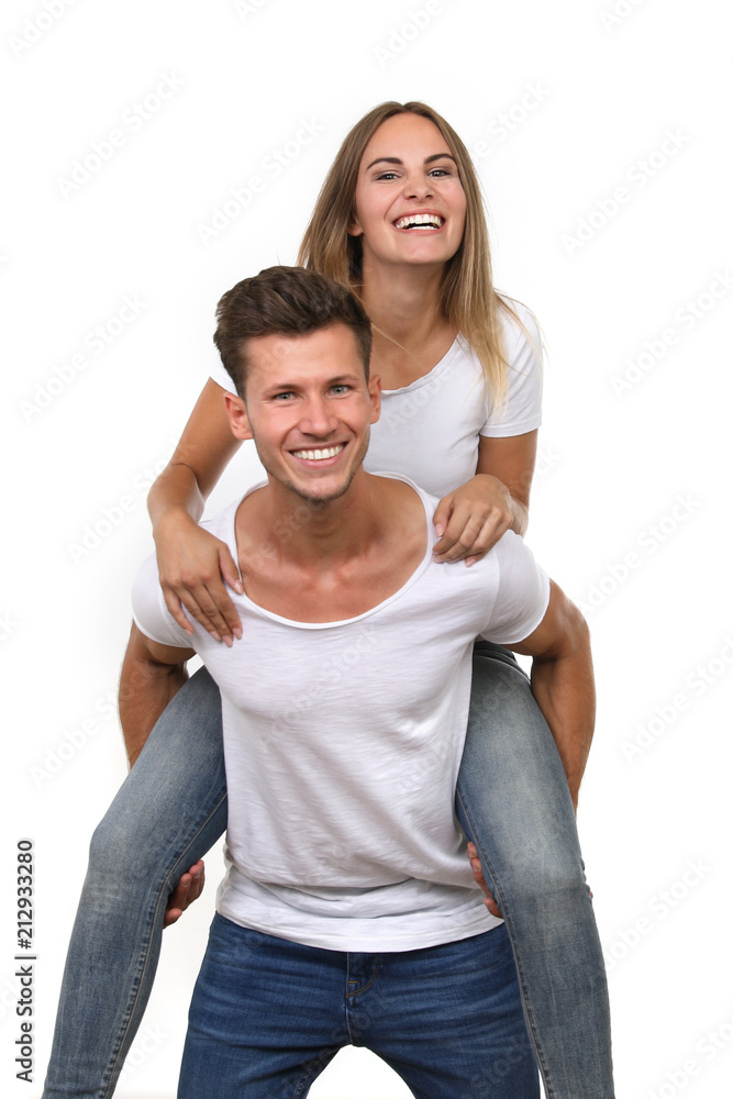 Junger Mann trägt junge Frau Huckepack vor weißem Hintergrund