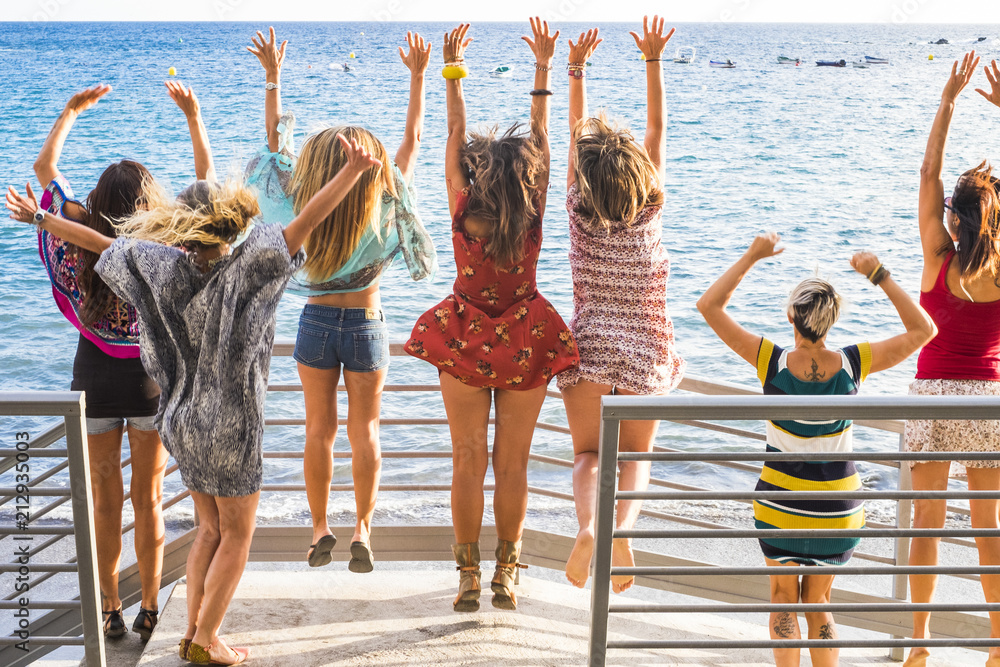 group of women enjoying and celebrate summer vacation all together saying  hallo to the ocean and the nature. young people leisure activity, all hands  up and vintage colors style. fashion dresses Stock