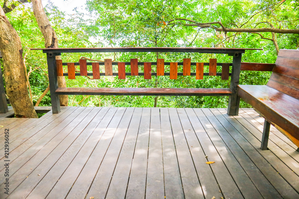 wood bench table and wood pettern floor and green tree sky garden