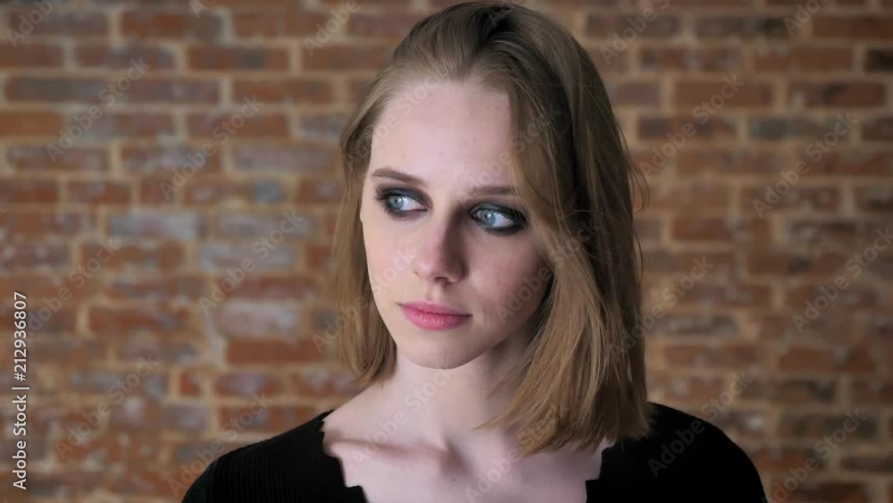 Young charming girl with smoky eyes is shaking head, playing hair, thinking concept, brick background Young charming girl with smoky eyes is shaking head, playing hair, thinking concept, brick background