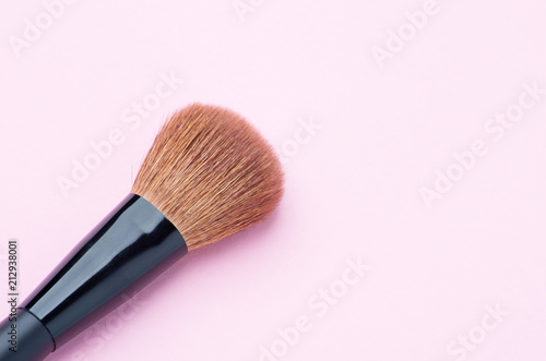 Makeup brush on pink background close up.