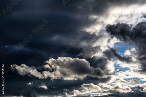 Dramatic dark rain clouds with a blue sky gap.