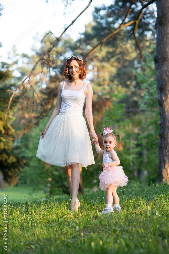 Mom and daughter are two years old sitting on the grass Mom and daughter are two years old sitting on the grass