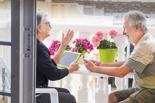 adult senior couple use laptop outdoor leisure activity at the terrace at home. smile and enjoy the nice weather and the retired life staying together all the days without work. use technology photo