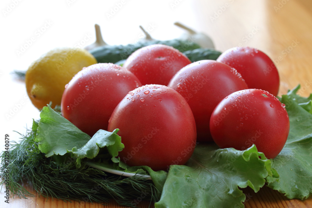 Group of red ripe tomatoes with water drops lie on a lettuce leaves Group of red ripe tomatoes with water drops lie on a lettuce leaves