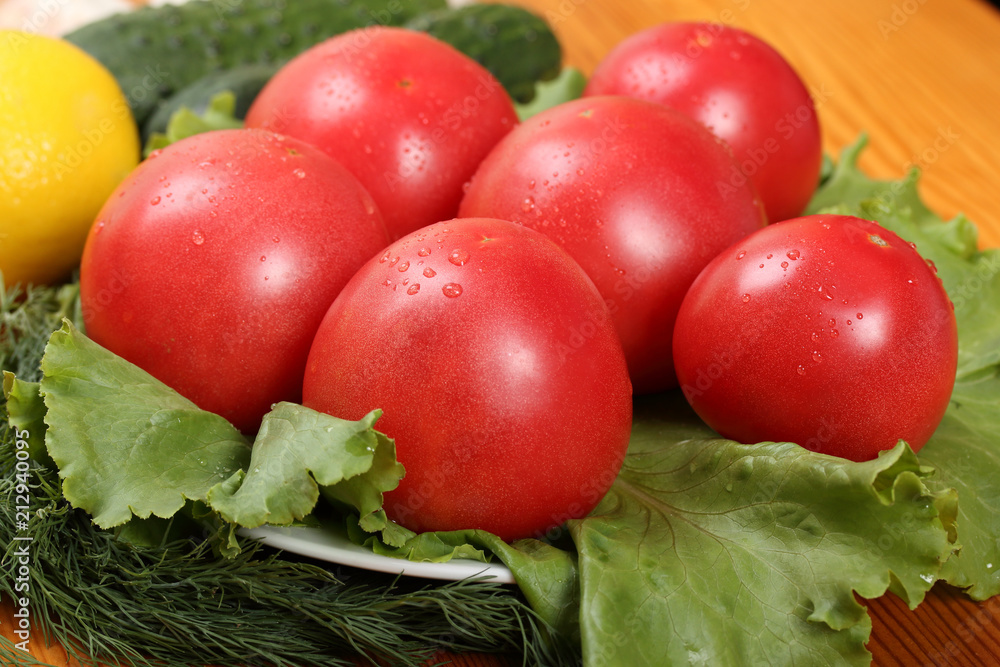 Group of six red ripe tomatoes with water drops lie on a lettuce leaves Group of six red ripe tomatoes with water drops lie on a lettuce leaves