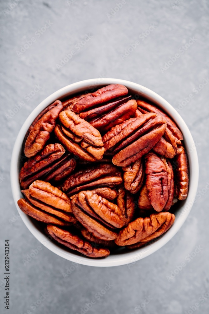 Raw pecan nuts in bowl on gray background. Raw pecan nuts in bowl on gray background.