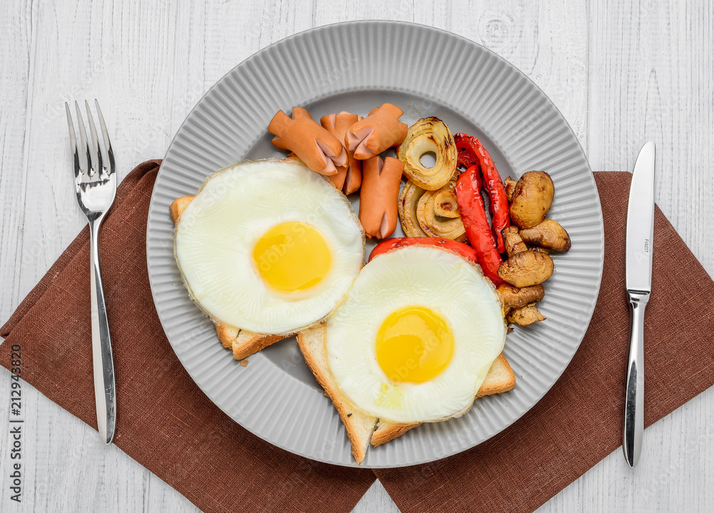 Set for breakfast fried eggs, grilled vegetables, sausages. Bread on a wooden table. Set for breakfast fried eggs, grilled vegetables, sausages. Bread on a wooden table.
