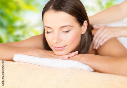 wellness  spa and beauty concept - close up of beautiful woman having massage over green natural background