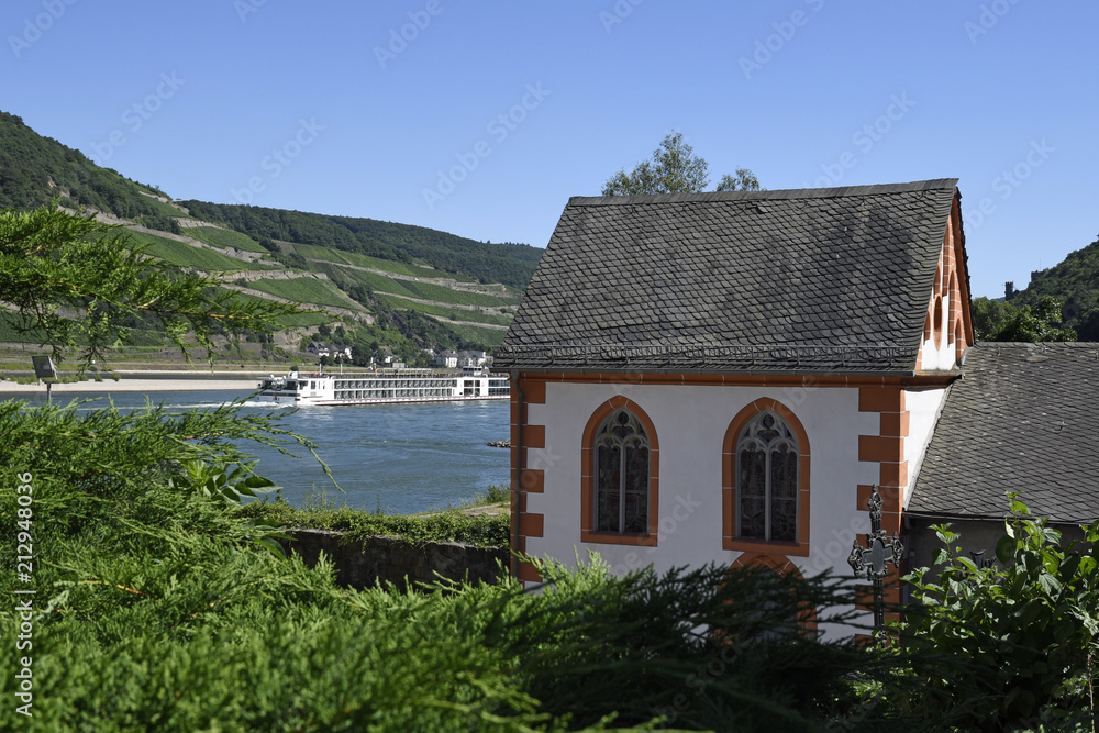ein flusskreuzfahrtschiff fährt auf dem rhein neben clemenskapelle und beinhaus bei trechtingshausen ein flusskreuzfahrtschiff fährt auf dem rhein neben clemenskapelle und beinhaus bei trechtingshausen