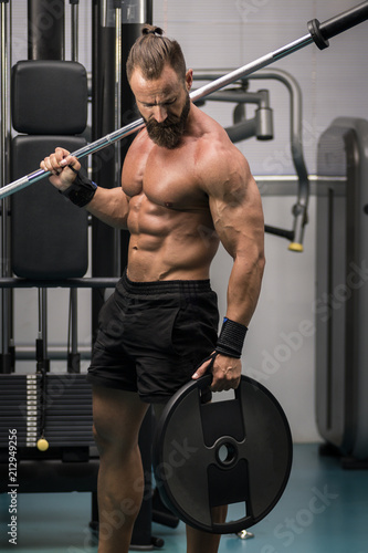 Hombre fuerte con grandes músculos preparando peso para entrenar en el gimnasio. Ponerse en forma.