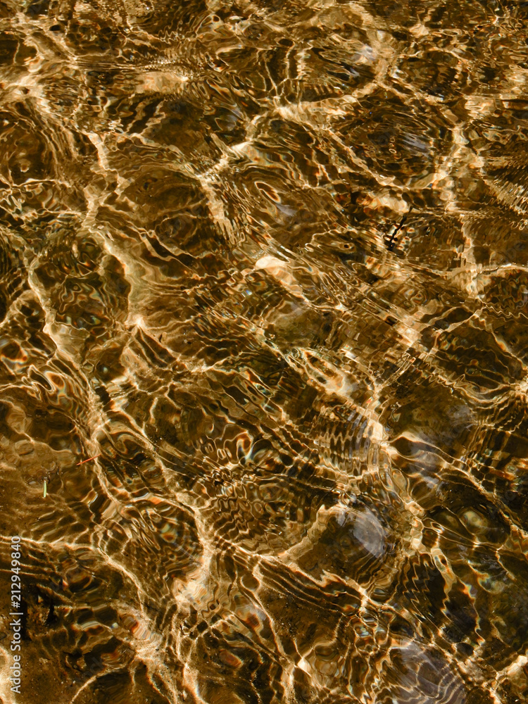 Caustic pattern produced by sunlight being refracted by the rippling water surface. The dispersion of light waves in water causes The dispersion of light waves in water causes the prism-like colors.