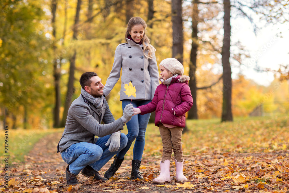 family, season and people concept - happy mother, father and little daughter with maple leaf at autumn park