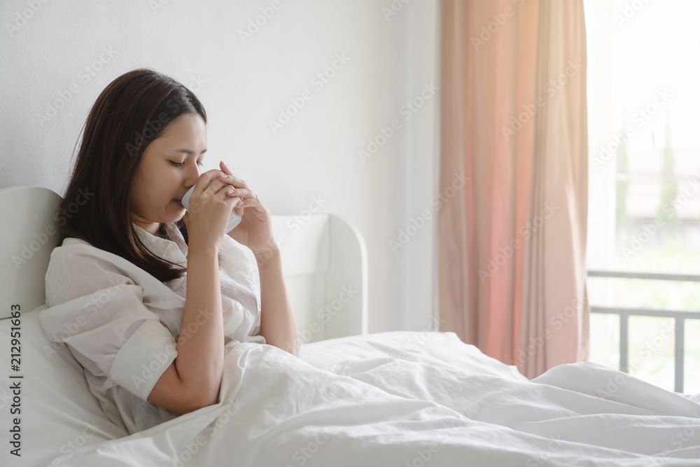 Young asian woman drinking morning coffee in bed. Young asian woman drinking morning coffee in bed.