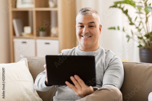 technology, people and lifestyle concept - man with tablet pc computer sitting on sofa at home