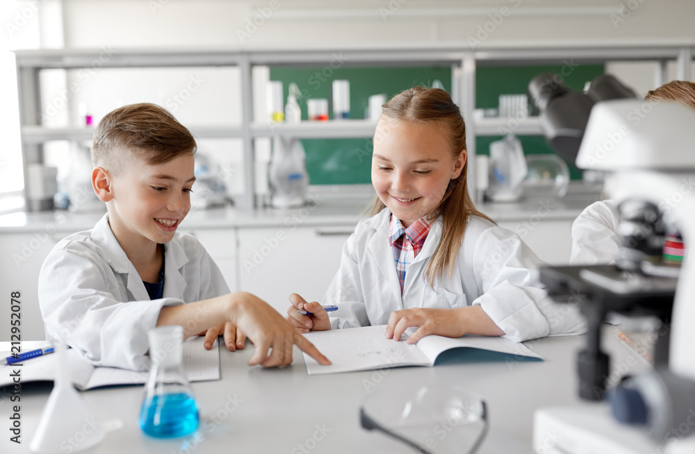 education, science and children concept - happy kids with workbooks studying chemistry at school laboratory education, science and children concept - happy kids with workbooks studying chemistry at school laboratory