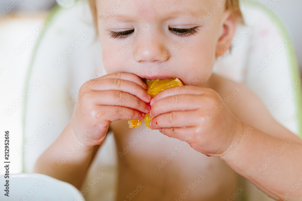 Portrait of adorable baby girl eating orange at home . Portrait of adorable baby girl eating orange at home .