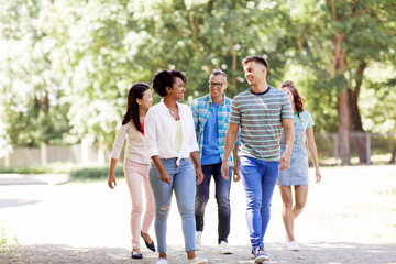 people, friendship and international concept - group of happy friends walking in park