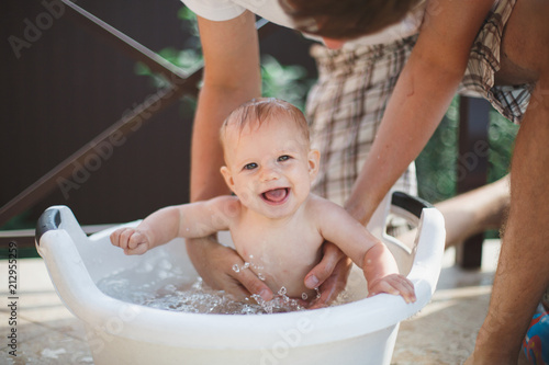 Fotografia, Obraz Mother bathing happy adorable baby girl in white basin .
