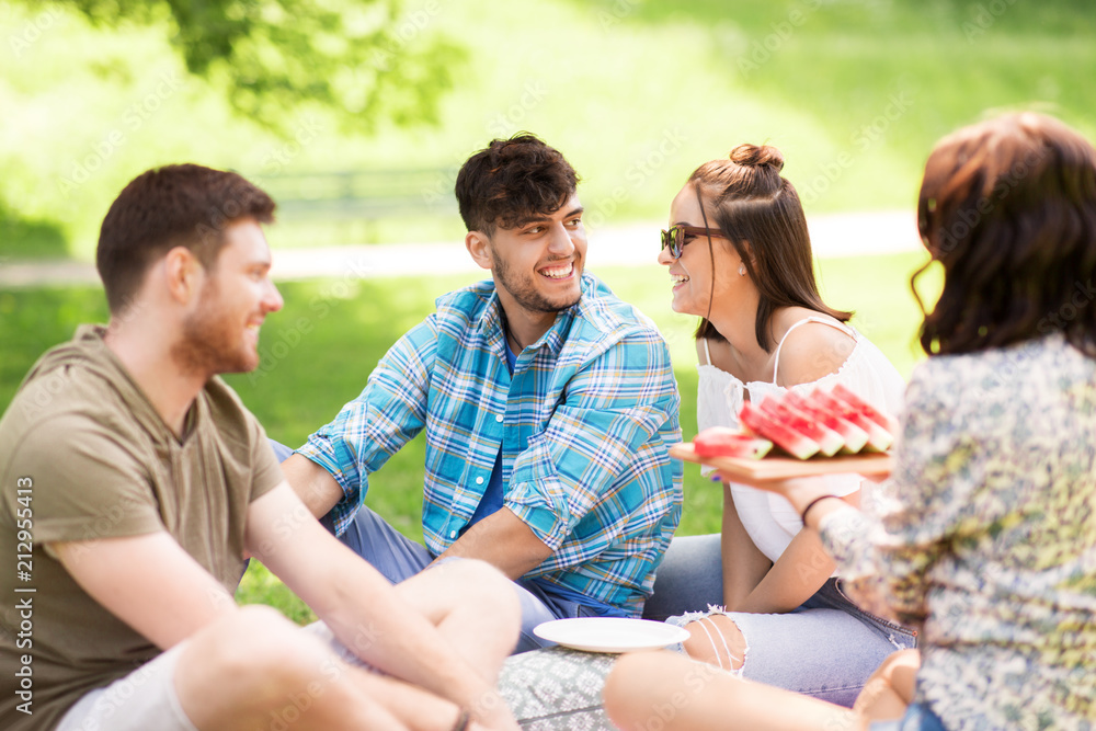 friendship, leisure and summer concept - group of happy friends eating watermelon at picnic in park friendship, leisure and summer concept - group of happy friends eating watermelon at picnic in park