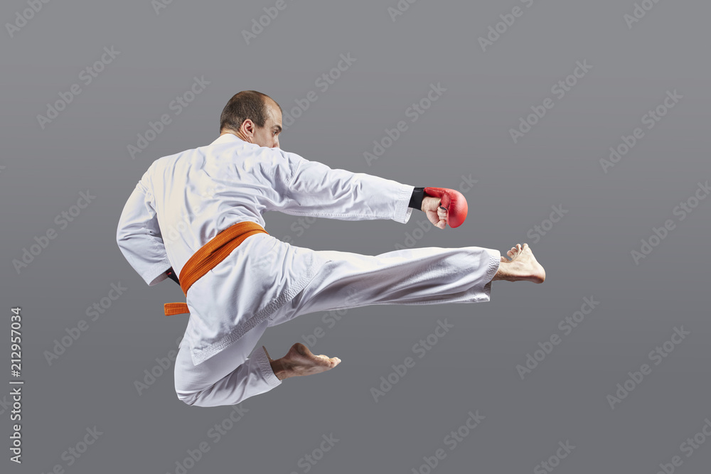 With an orange belt, an athlete beats a kick in a jump With an orange belt, an athlete beats a kick in a jump