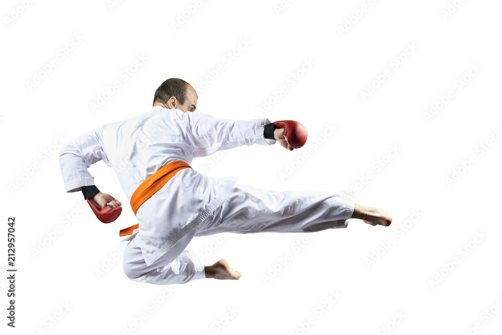 On a white background, an athlete beats a kick in a jump On a white background, an athlete beats a kick in a jump