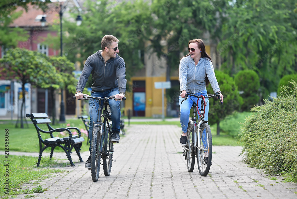 young couple riding bicycle together in a park