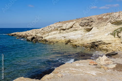 It shows the rocky coast of the Mediterranean, beautiful blue waters and blue sky