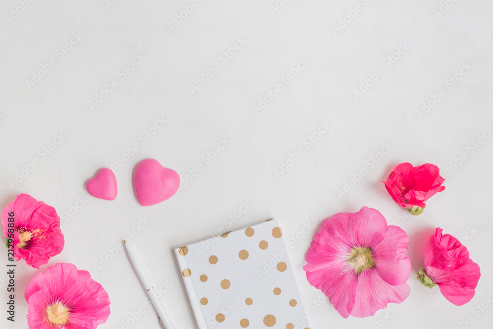 Flat lay desk with pink flowers, notebook and accessories Flat lay desk with pink flowers, notebook and accessories