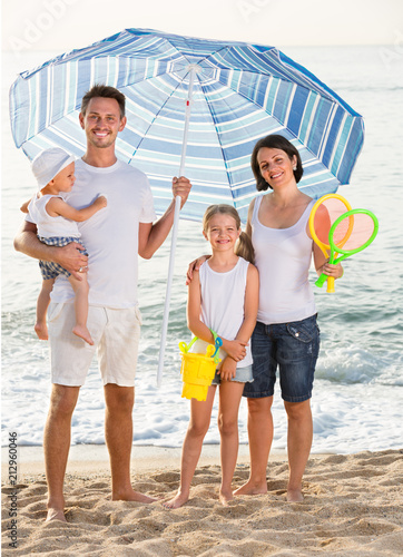family standing under sun umbrella