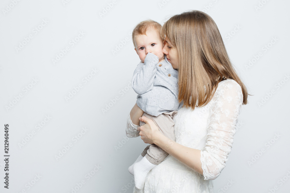 Young mother holding baby girl standing over white background. Young mother holding baby girl standing over white background.