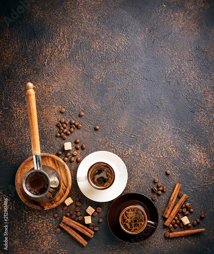 Cups of coffee, beans, sugar and cinnamon photo