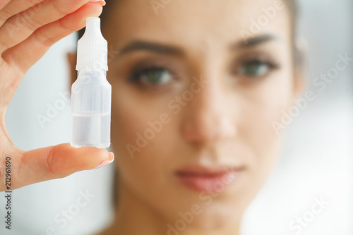 Fototapeta Naklejka Na Ścianę i Meble -  Vision And Medicine Concept. Young Girl Holds Eye Drops In Hands. Portrait of a Beautiful Woman with Contact Lenses. Healthy Look. High Resolution