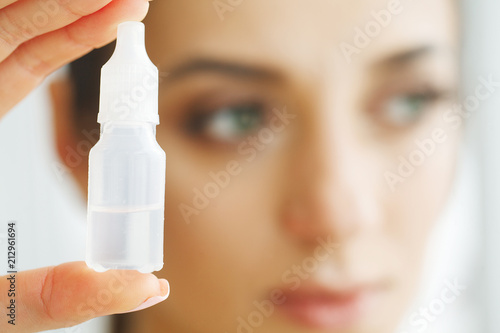 Vision And Medicine Concept. Young Girl Holds Eye Drops In Hands. Portrait of a Beautiful Woman with Contact Lenses. Healthy Look. High Resolution