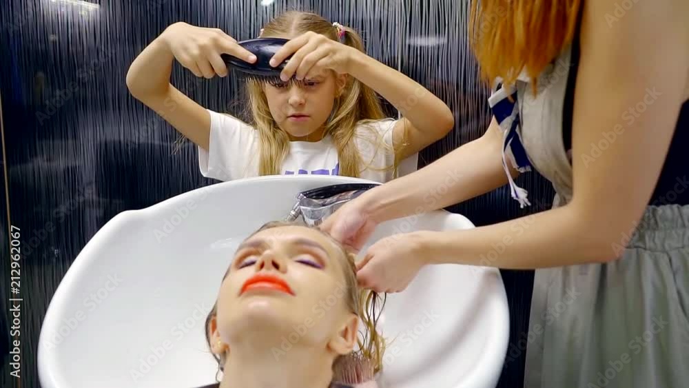 head washing procedure in the beauty salon. the girl helps to comb wet hair client head washing procedure in the beauty salon. the girl helps to comb wet hair client