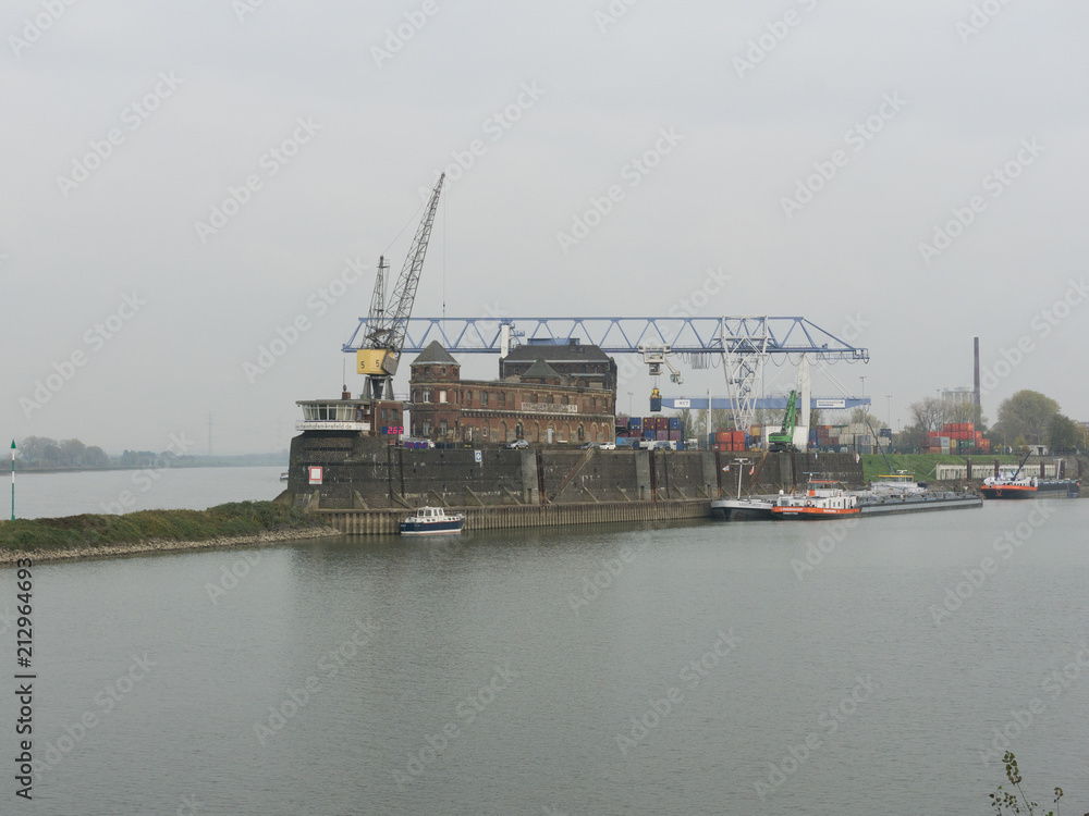 Old shipyard on the river bank in cloudy weather with ships and cranes