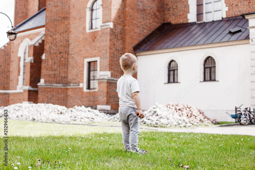 A child with stones. The boy is playing around the historic building. In the courtyard near the church. Little boy