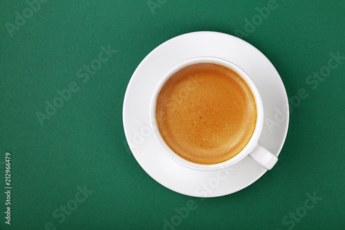 Фотография White cup of espresso coffee on saucer on green