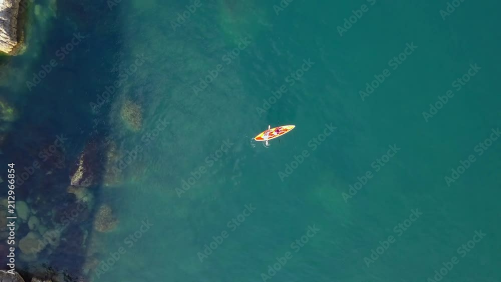 aerial overhead 4k shot of two men in kayak canoe in the sea near rock coast aerial overhead 4k shot of two men in kayak canoe in the sea near rock coast