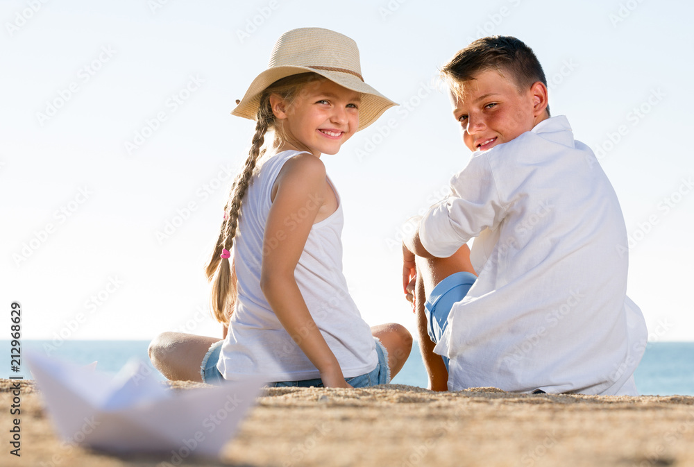 ﻿boy and girl sitting on sandy beach