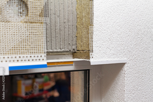 Layered insulated wall with plaster, glue, net, polystyrene, thermal protection and plastic window sill