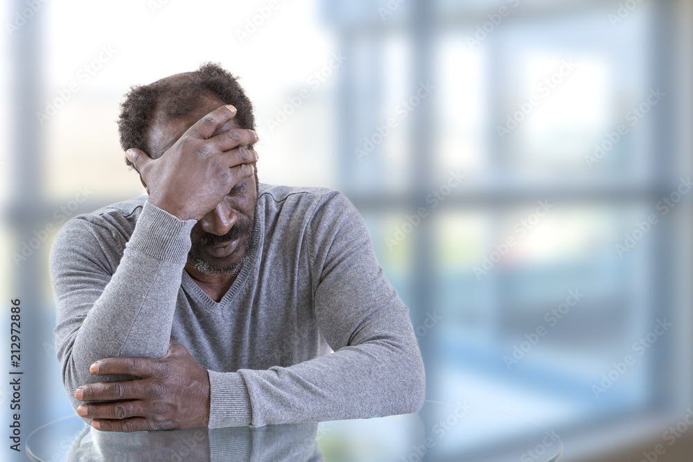 Closeup portrait unhappy upset guy, sad middle age man bothered by mistakes hands on head eyes over bright office background Closeup portrait unhappy upset guy, sad middle age man bothered by mistakes hands on head eyes over bright office background