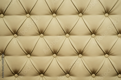 Coach-type leatherette screed tightened with buttons. Natural chesterfield style quilted upholstery backdrop close up. background texture
