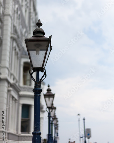 Light post on the road. Street light post. Street lamp on the road. Cast iron street lamp. Designer lamp post. Lamps on the top of lamppost. Street road light.