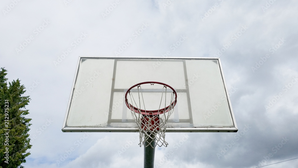 Basketball board front view with cloudy sky and tree top