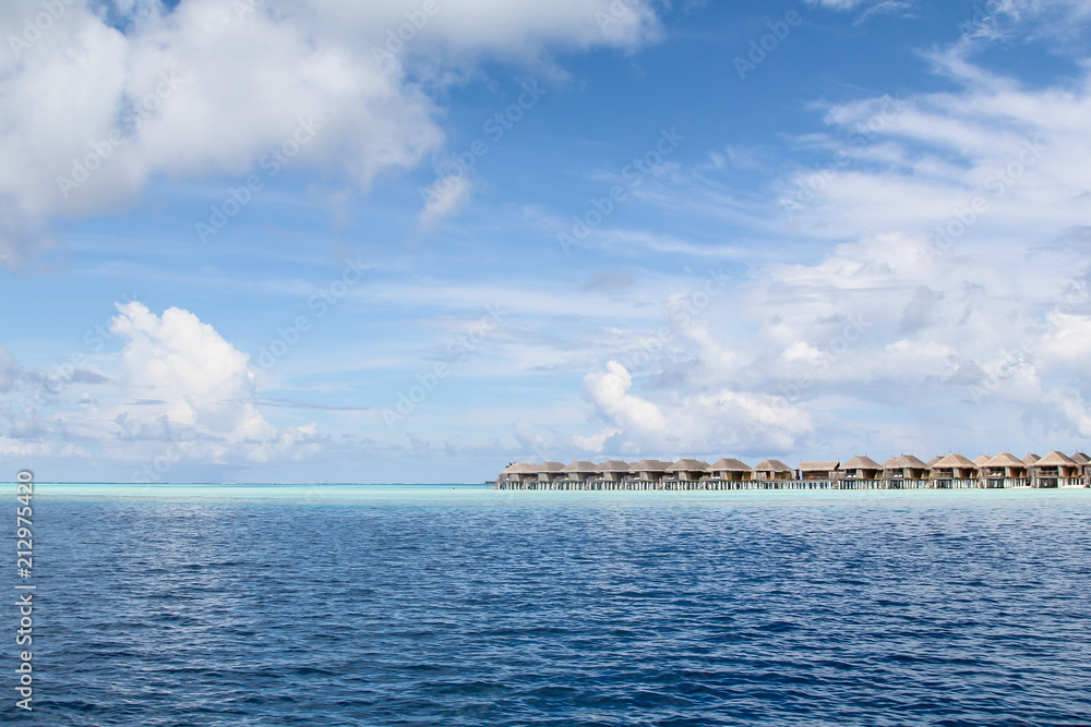 Seaside wooden bungalows on a shallow reef in a luxury resort on a tropical island in the atoll of the Maldives